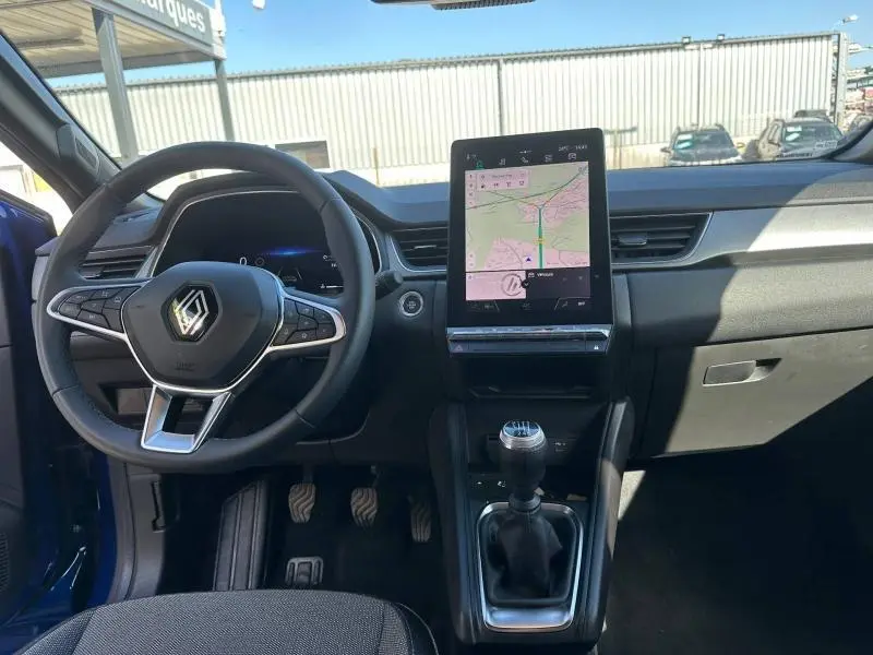 Vue intérieure avant du Renault Captur 2025 Bleu Iron/Noir Etoilé, avec volant multifonctions et écran tactile vertical.