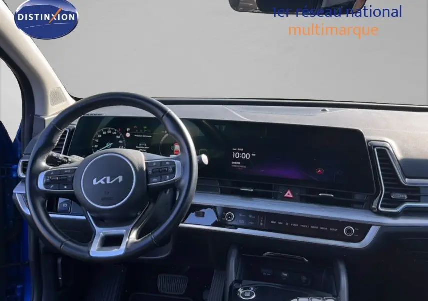 Vue intérieure du tableau de bord et volant du Kia Sportage bleu fusion métal, avec écran digital large et commandes au volant.