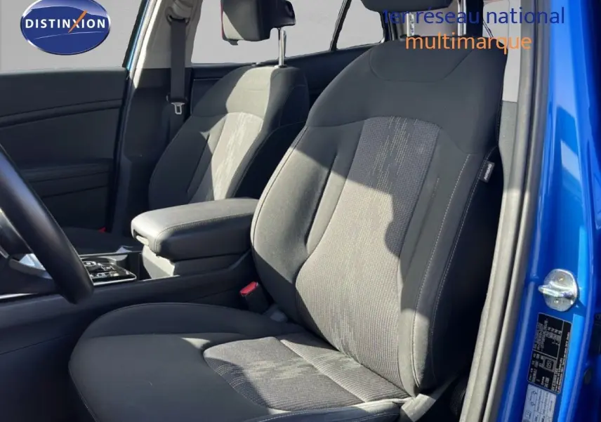 Vue intérieure côté conducteur du Kia Sportage bleu fusion métal 2022, sièges tissu noir avec accoudoir central.