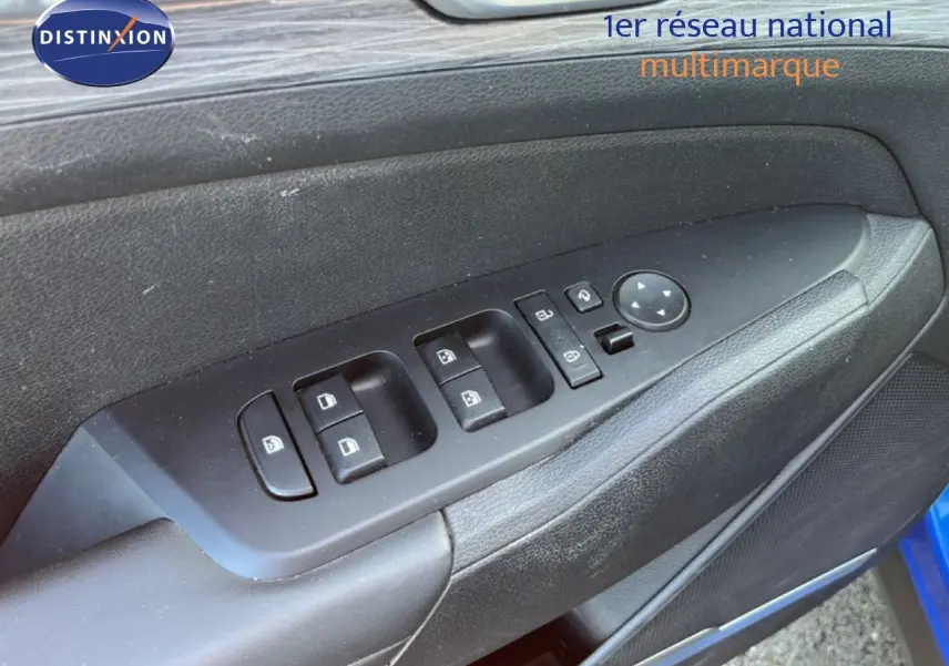 Gros plan sur les commandes des vitres et rétroviseurs sur la porte côté gauche d'un Kia Sportage bleu fusion métal.