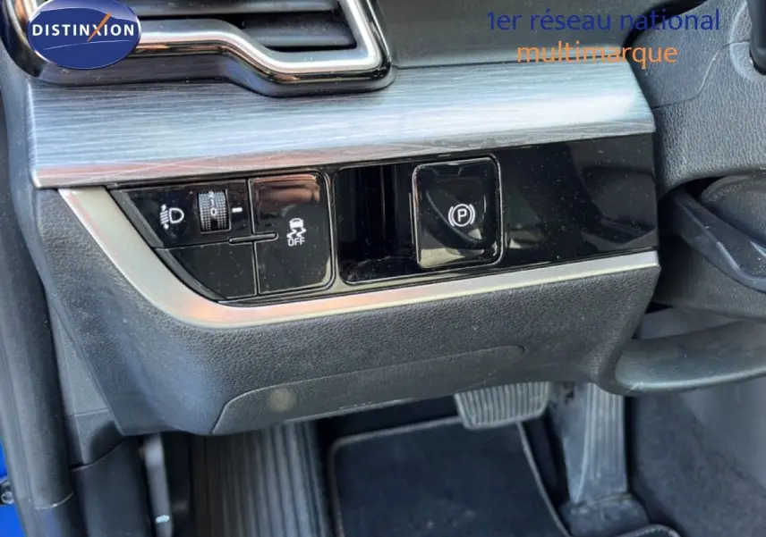 Gros plan sur les commandes sous le tableau de bord côté gauche du Kia Sportage bleu fusion métal 2022, avec bouton de frein à main électrique.