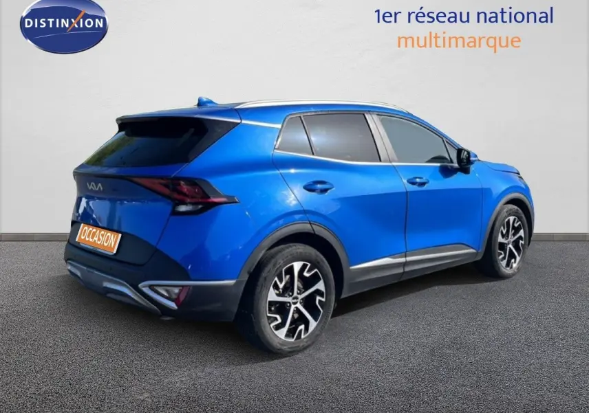 Vue 3/4 arrière droite d'un Kia Sportage bleu fusion métal avec jantes alliage noires et détails chromés.