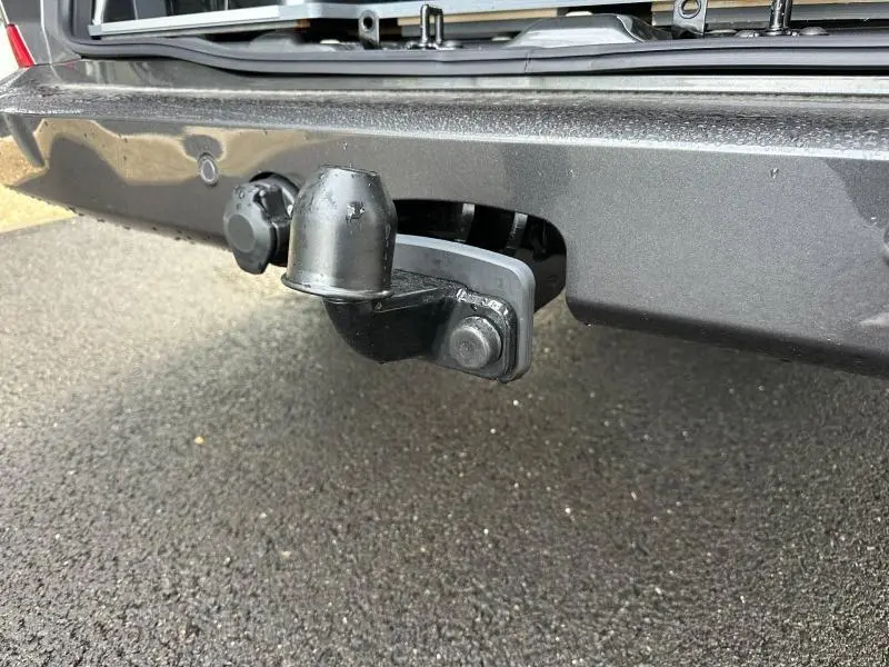 Gros plan sur l'attelage d'un Volkswagen Transporter FGN gris 2025, vue centrée sous le pare-chocs arrière.