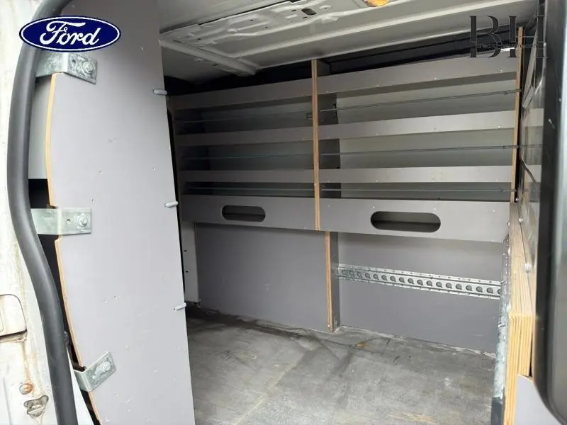 Vue intérieure arrière du Citroën Jumpy blanc Banquise, montrant les étagères et le plancher bois du coffre utilitaire.