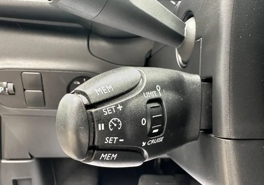 Gros plan sur la commande de régulateur de vitesse noire dans l’habitacle d’une Citroën C3 blanche Banquise 2023.