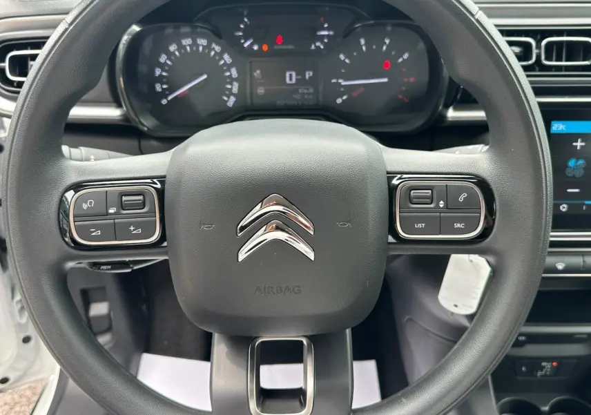 Vue rapprochée du volant noir de la Citroën C3 2023, avec tableau de bord et commandes intégrées visibles.