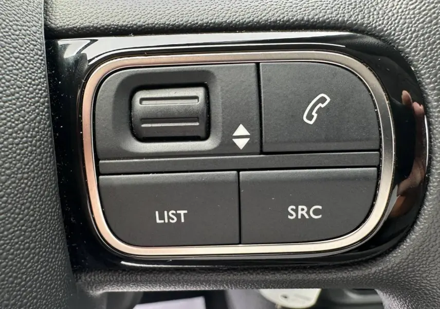 Gros plan sur les commandes noires du volant de la Citroën C3 2023, boutons pour téléphone et audio.