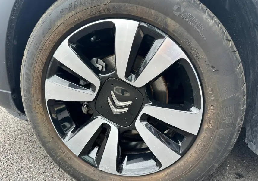 Gros plan sur la jante alu bicolore noire et argentée d'une Citroën C3 Blanc Banquise, avec logo Citroën central visible.