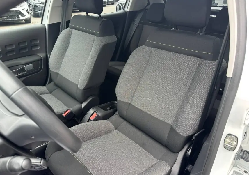 Vue intérieure sur les sièges avant gris tissu Mica Grey d'une Citroën C3 Blanc Banquise, porte ouverte côté droit.