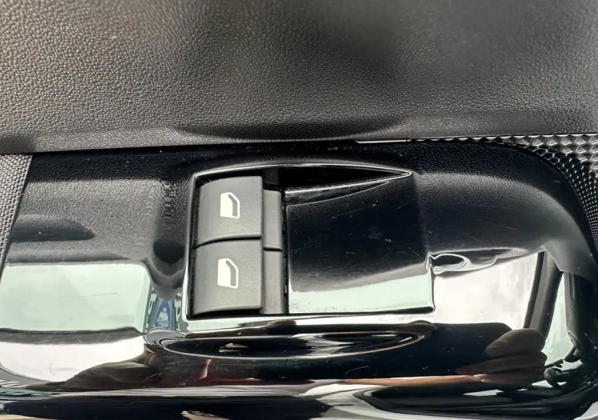 Gros plan sur les commandes de lève-vitres électriques côté conducteur de la Citroën C3 blanche Banquise.