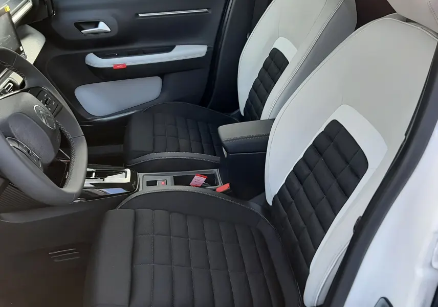 Vue intérieure côté conducteur de la Citroën C3 Aircross 2026, sièges bi-ton noir et blanc avec console centrale visible.