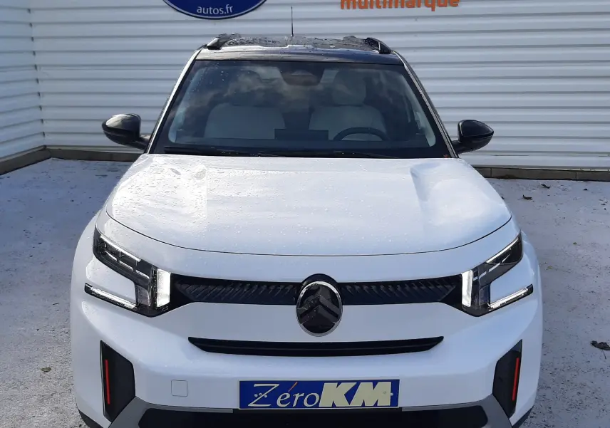 Vue avant d'une Citroën C3 Aircross 2026 blanc avec toit noir, feux LED et plaque Zéro KM visible.