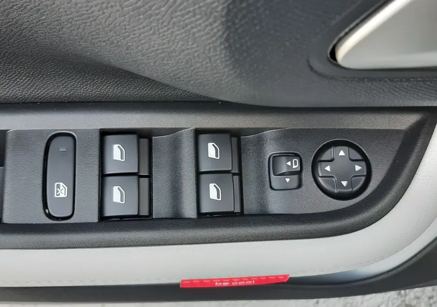 Gros plan sur les commandes de lève-vitres et réglage des rétroviseurs côté conducteur d'une Citroën C3 Aircross blanc toit noir.