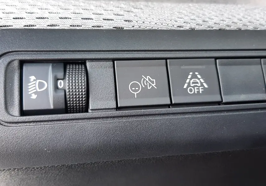 Gros plan sur les commandes intérieures du Citroën C3 Aircross 2026, avec réglage des phares et boutons d'assistance à la conduite.
