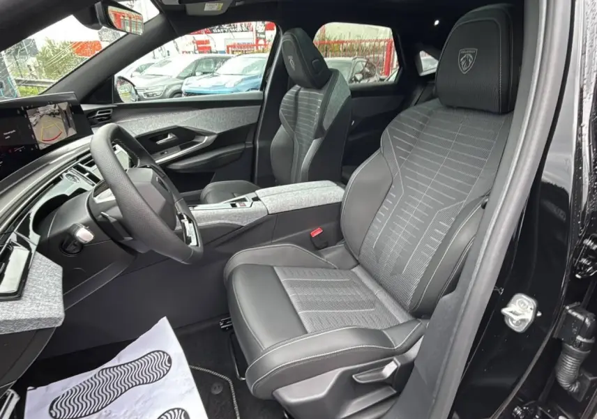 Vue intérieure côté conducteur du Peugeot 3008 gris titane, mettant en valeur les sièges Alcantara embossés et le tableau de bord moderne.