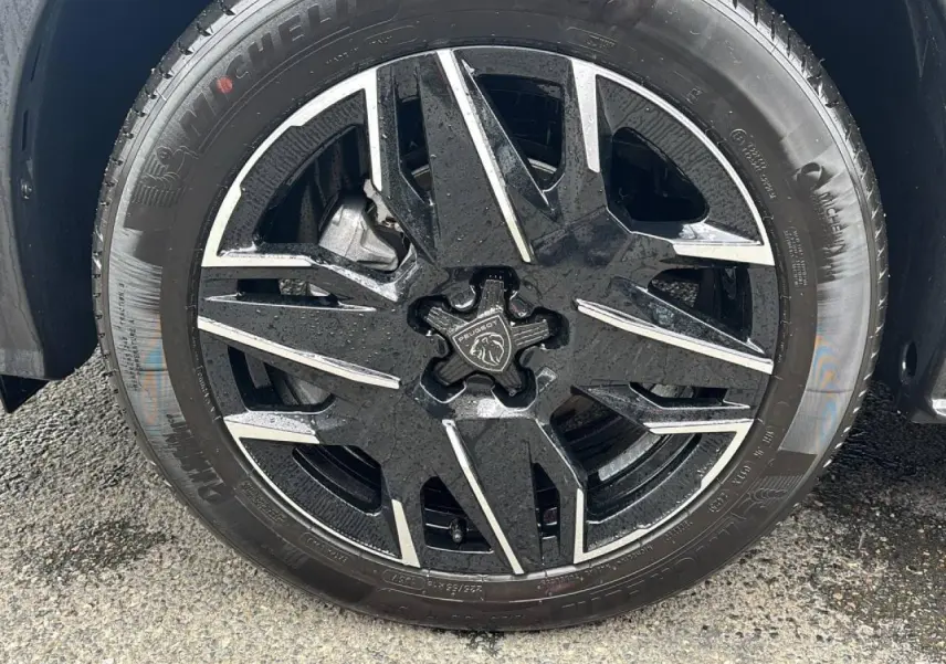 Gros plan sur la jante alliage 19'' diamantée noire et argentée du Peugeot 3008 gris titane, avec logo Peugeot central.