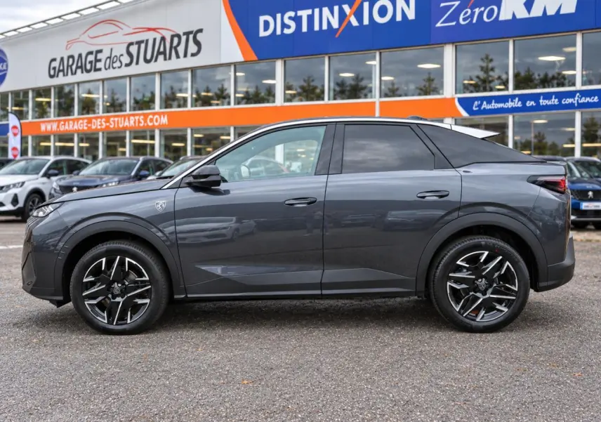 Vue latérale droite du Peugeot 3008 gris titane avec jantes alliage 19 pouces diamantées, stationné devant un garage.
