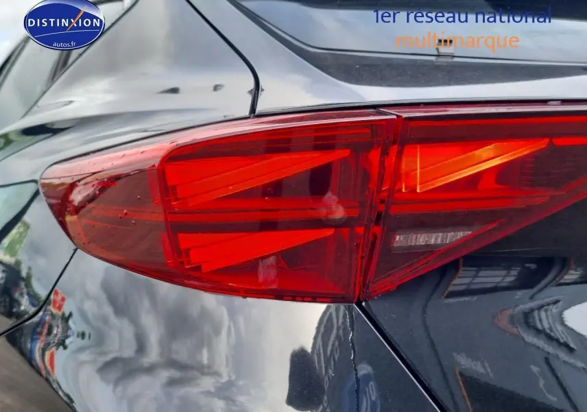 Gros plan sur le feu arrière gauche rouge vif du CUPRA Formentor noir midnight 2025, reflétant l'environnement urbain.