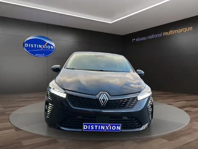 Vue frontale d'une Renault Clio V noire 2025 avec feux LED allumés et calandre au logo chromé dans un showroom.