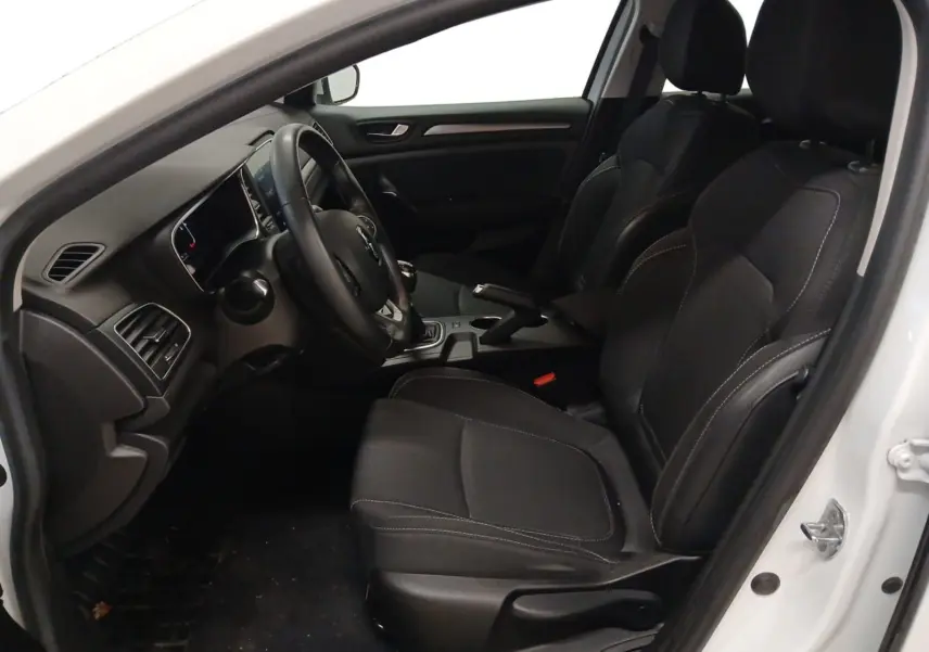 Vue intérieure côté conducteur de la Renault Mégane IV blanche, montrant les sièges noirs et le tableau de bord.