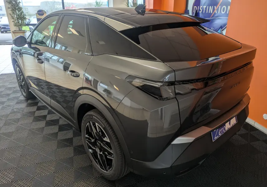 Vue 3/4 arrière droite du Peugeot 3008 gris titanium hybride, avec jantes noires et vitres teintées en showroom.