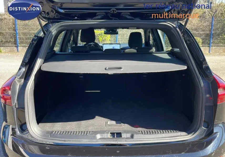 Vue arrière du coffre ouvert d'une Ford Focus SW 1.5 EcoBlue noire, mettant en valeur l'espace de chargement et la tablette cache-bagages.