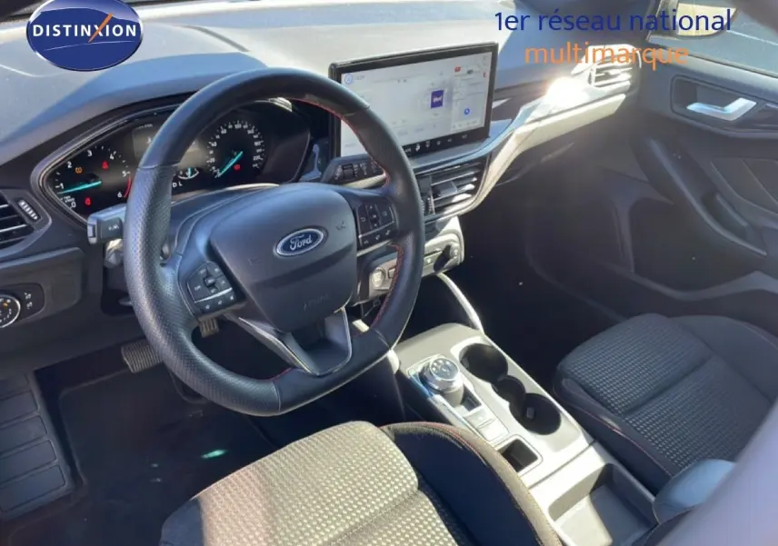 Vue intérieure côté conducteur de la Ford Focus SW noire, avec volant cuir, écran tactile et console centrale moderne.