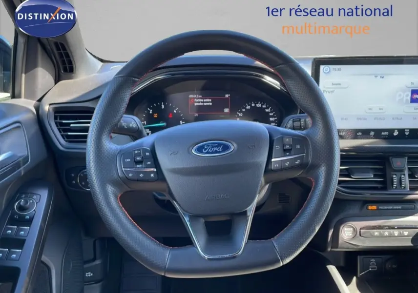 Vue centrée sur le volant en cuir perforé de la Ford Focus SW 2024 noir agate, avec tableau de bord et écran tactile visibles.