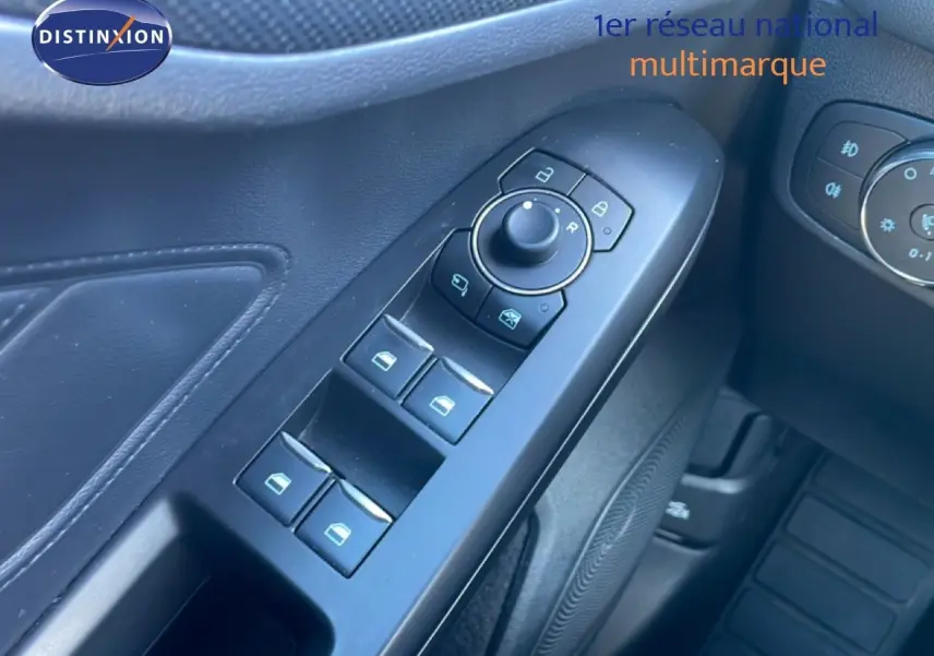Gros plan sur les commandes de lève-vitres et rétroviseurs côté conducteur d'une Ford Focus SW noire 2024.