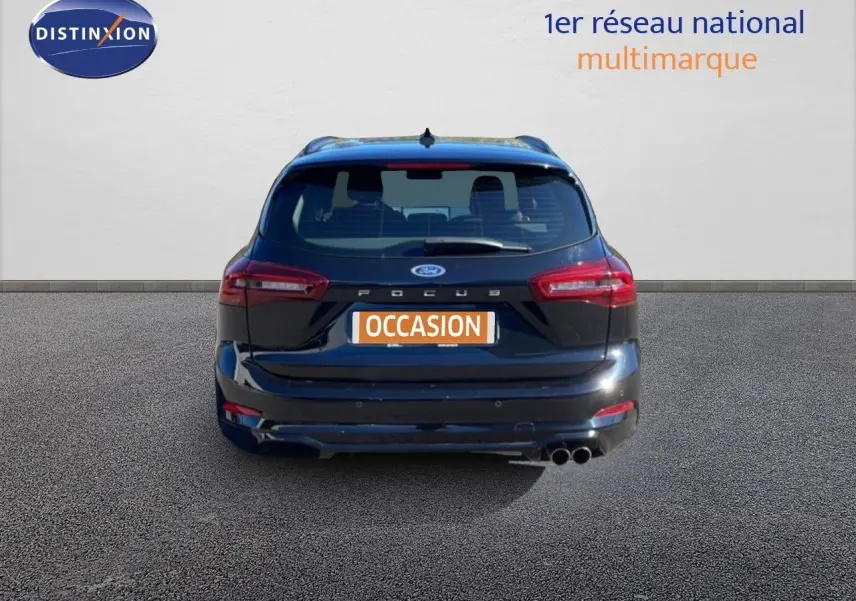 Vue arrière d'une Ford Focus SW noire Agate Metal avec double sortie d'échappement et logo Ford visible.