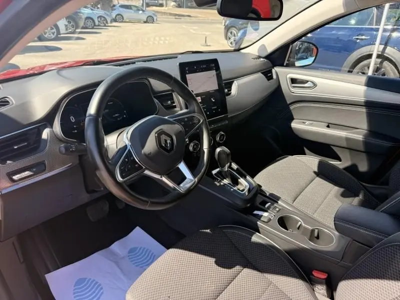 Vue intérieure côté conducteur du Renault Arkana 1.6 E-Tech rouge flamme, avec tableau de bord numérique et écran tactile vertical.