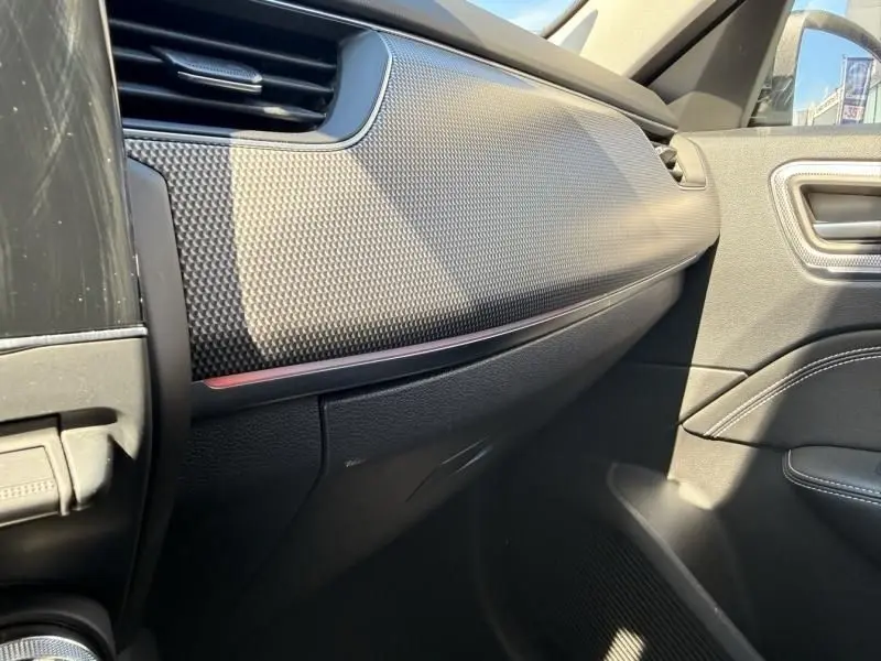 Vue intérieure côté passager du Renault Arkana 2022, tableau de bord texturé avec bande rouge discrète.