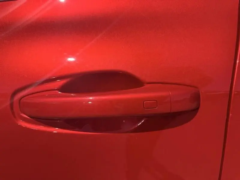 Poignée de porte rouge flamme du Renault Arkana 1.6 E-Tech 145 cv Intense, vue en gros plan côté gauche.