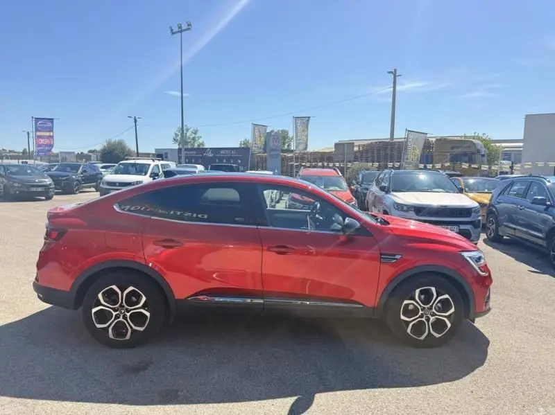 Profil droit du Renault Arkana rouge flamme 2022, version hybride Intense avec jantes distinctives en alliage.