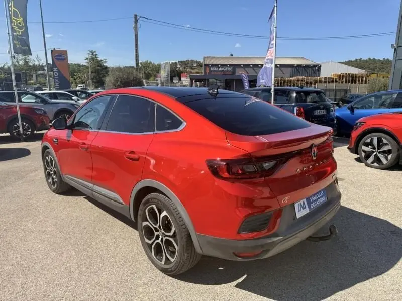 Vue 3/4 arrière droite du Renault Arkana rouge flamme 2022 avec toit noir et jantes distinctives cinq branches.