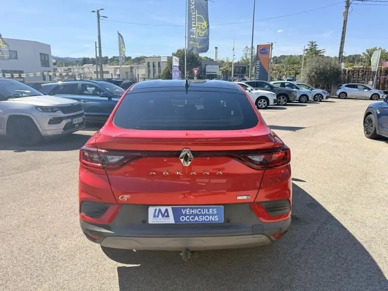 Vue arrière d'un Renault Arkana rouge flamme 2022 avec logo et feux LED, stationné en extérieur sur un parking.