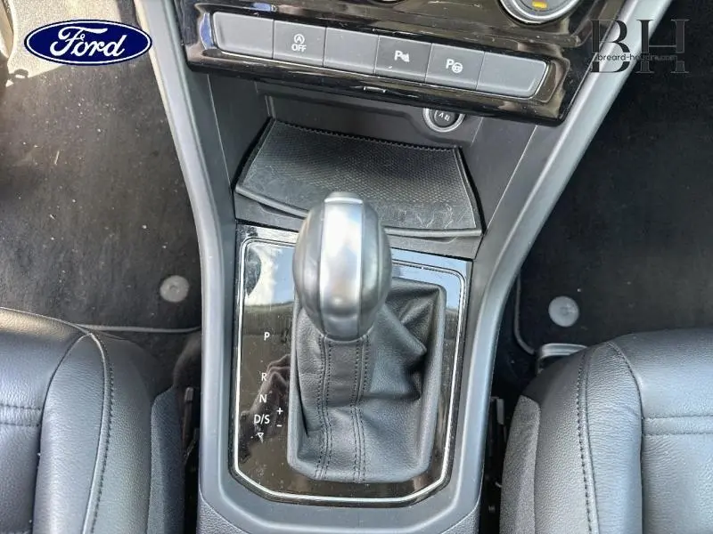 Le levier de vitesses automatique en cuir noir du Volkswagen Touran 2.0 TDI, vu de dessus entre les sièges avant.