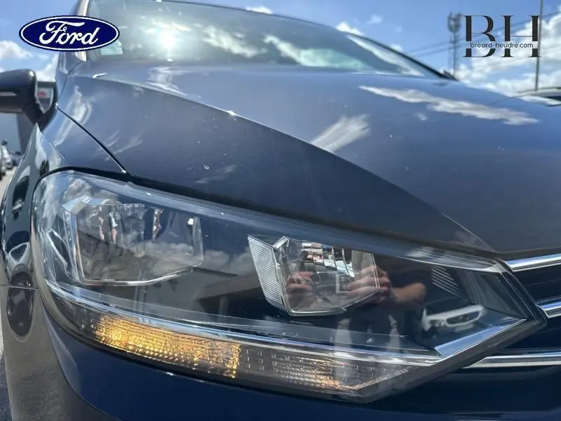 Gros plan sur le phare avant gauche du Volkswagen Touran noir intense nacré, mettant en valeur les détails du bloc optique.