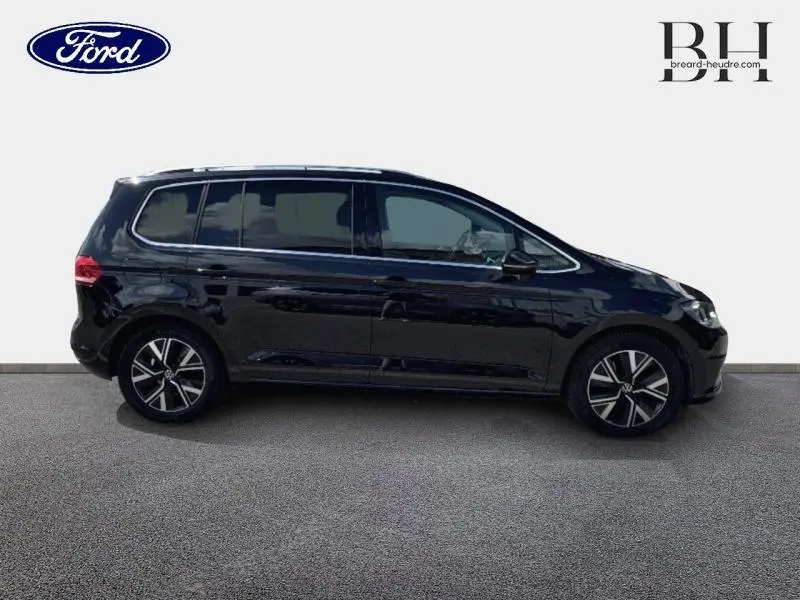 Profil droit d'un Volkswagen Touran noir intense nacré, avec jantes alliage et vitres teintées sur fond neutre.