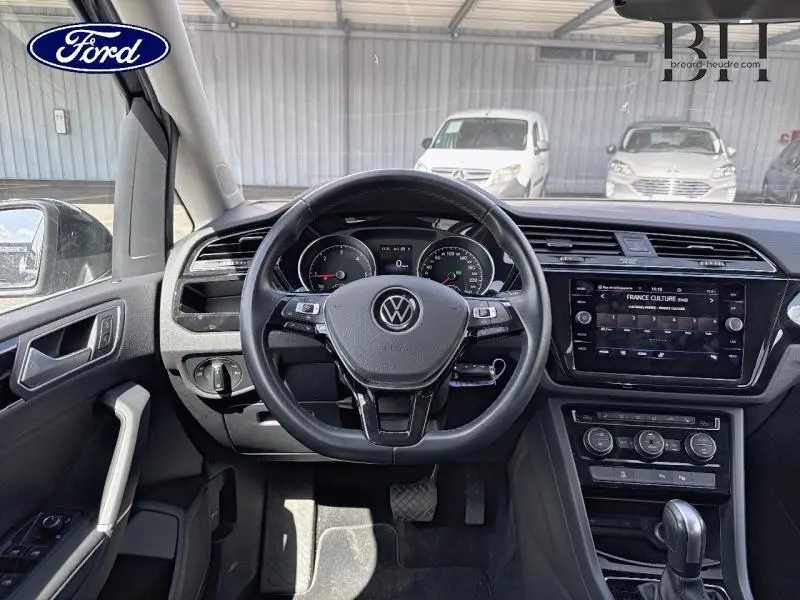 Vue intérieure centrée sur le volant cuir noir et tableau de bord du Volkswagen Touran 2020, avec écran tactile et commandes au volant.
