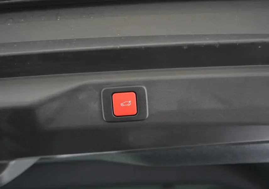 Bouton rouge d'ouverture électrique du hayon visible à l'intérieur du coffre du Peugeot 3008 gris Artense 2026.