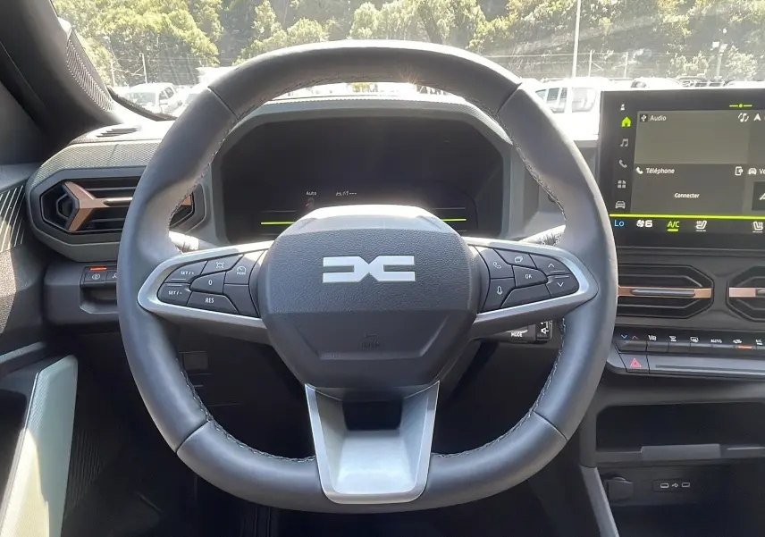 Vue rapprochée du volant multifonction du Dacia Duster 2025 avec tableau de bord numérique et écran tactile.