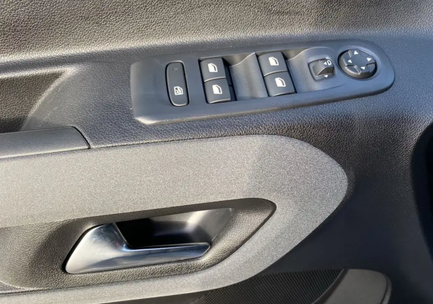 Gros plan sur la commande des vitres et poignée intérieure côté gauche du PEUGEOT RIFTER 2025 en gris acier.
