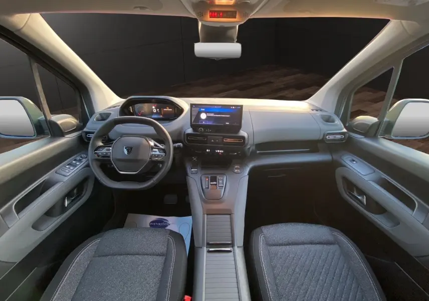 Vue intérieure avant du Peugeot Rifter gris acier 2025, tableau de bord moderne avec écran tactile central et volant multifonction.