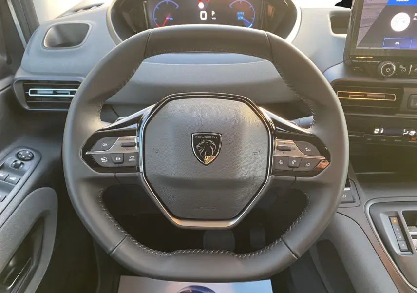 Vue centrée du volant cuir noir du Peugeot Rifter 2025 avec tableau de bord numérique et écran tactile multifonction.