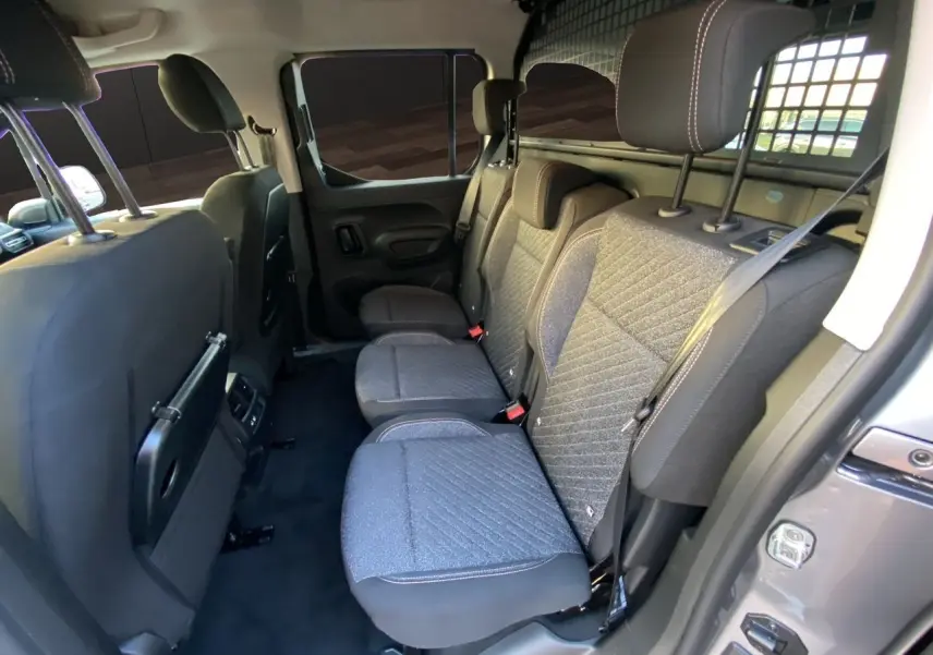 Vue intérieure côté droit sur les sièges arrière gris tissu du Peugeot Rifter 2025 avec cloison métallique de séparation.