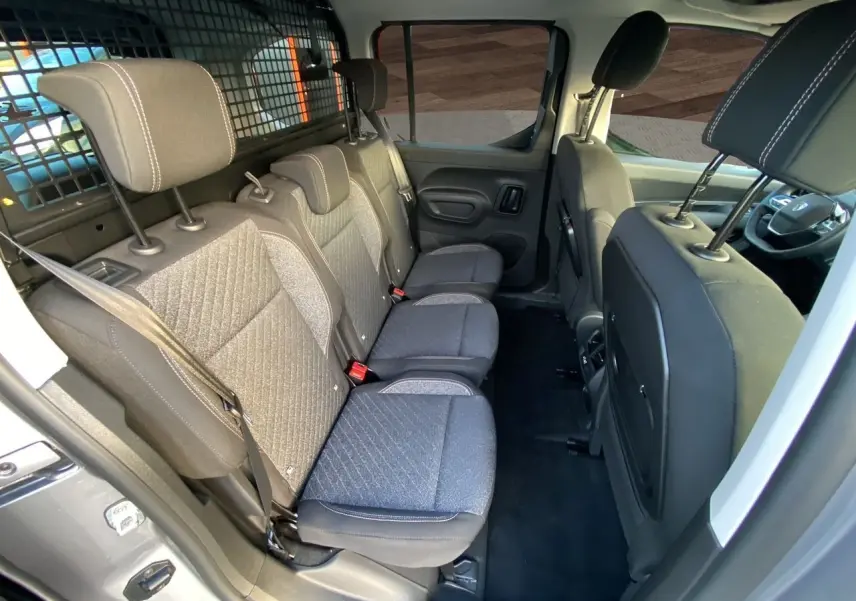 Vue intérieure côté droit des sièges arrière gris tissu du Peugeot Rifter 2025 avec cloison de séparation métallique.