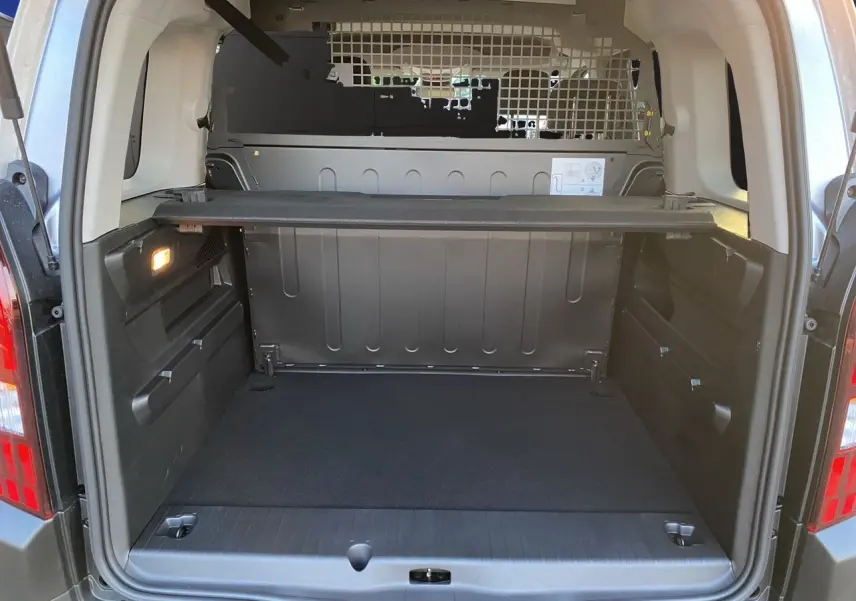 Coffre ouvert vu de l'arrière du Peugeot Rifter gris acier avec cloison métallique et tablette de séparation.