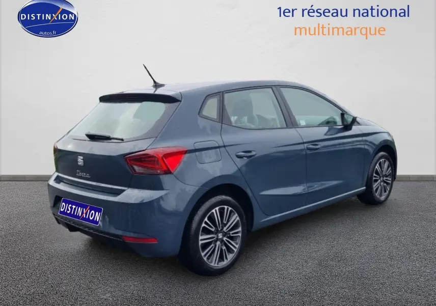 Vue 3/4 arrière droite d'une SEAT Ibiza 2025 bleu métallisé avec jantes alliage et feux arrière triangulaires.