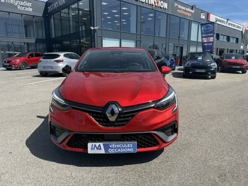 Vue de face d'une Renault Clio V rouge flamme RS Line 2022, avec calandre noire et logo Renault bien visible.